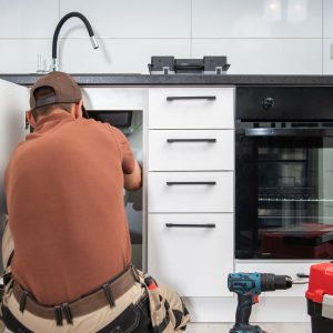 Plumbing Technician Finishing Kitchen Sink Pipeline Installation Caucasian Plumbing Technician in His 40s Finishing Kitchen Sink Pipeline Installation. New and Modern Kitchen Remodeling. Home Improvement Theme.
